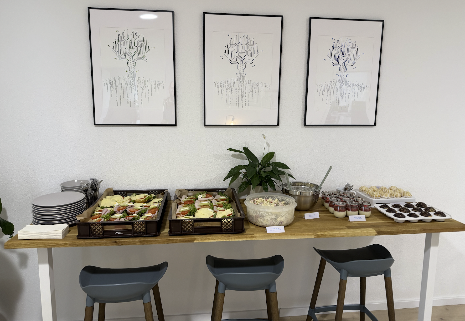 Buffet bei Flowd: Trays mit belegten Brötchen, Salaten, Muffins und Cupcakes auf einem Holztisch